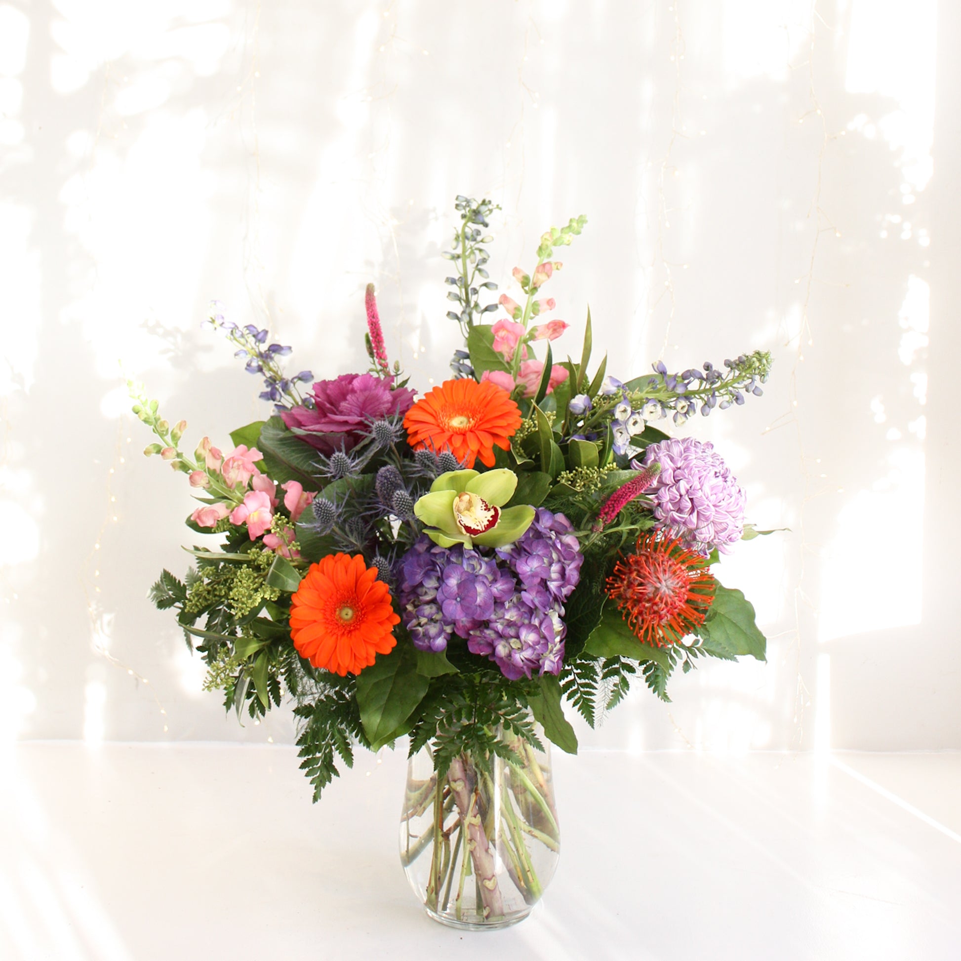 selection of bright and bold flowers in tall vase arrangement hydrangea roses eucalyptus. Designed at oleander floral design in toronto offering same day delivery