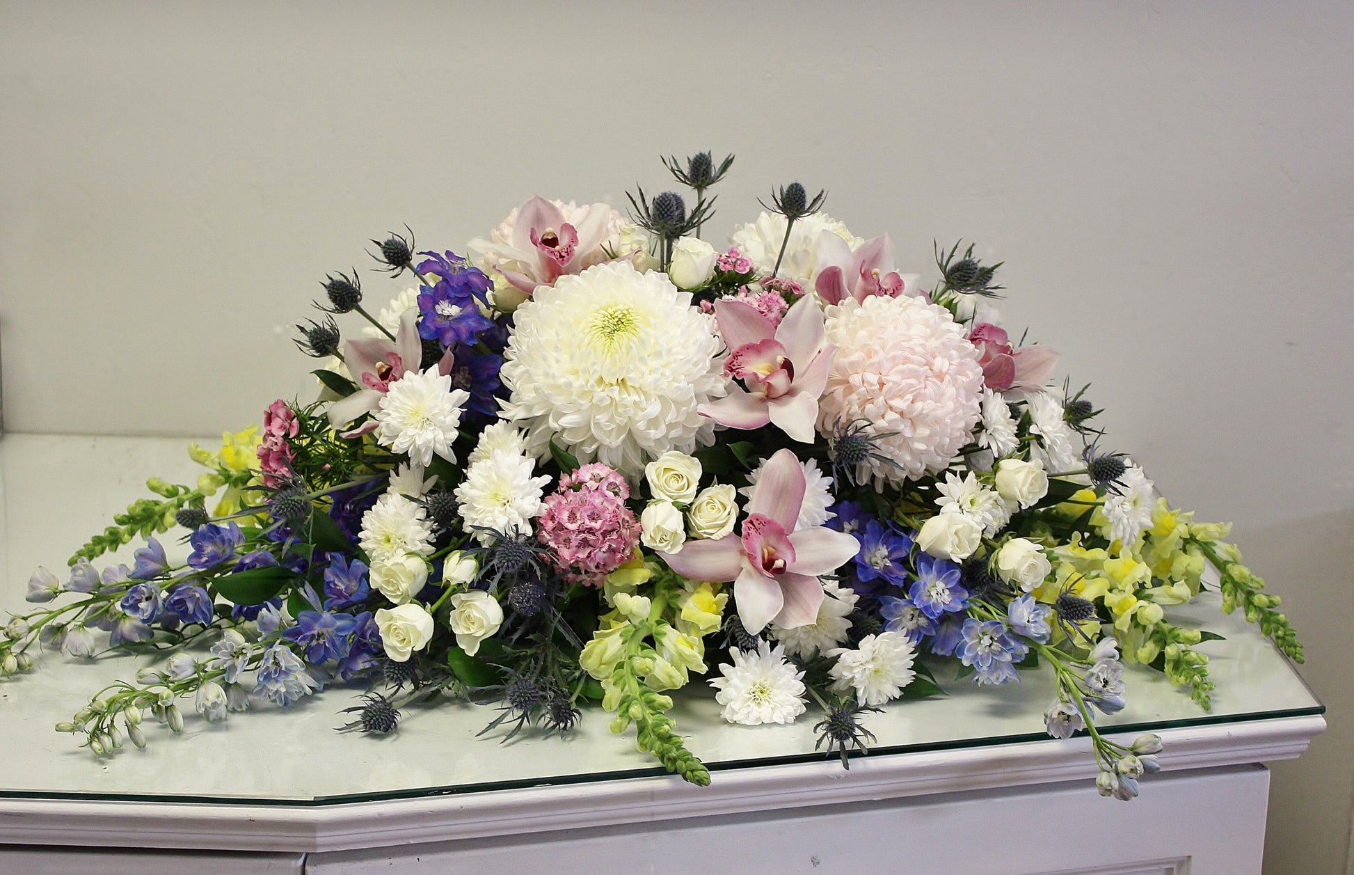 casket spray oleander floral design toronto same day flower delivery sympathy funeral etobicoke white and green flowers orchid rose eucalyptus delphinium pink blue yellow